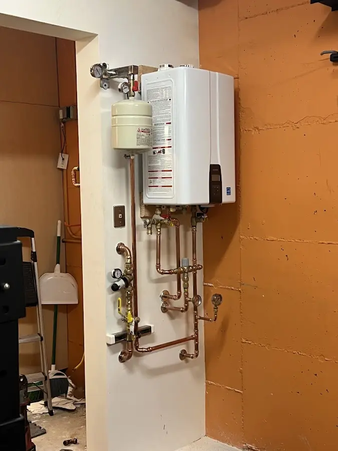 Plumbing technician inspecting water heater connections in Barre